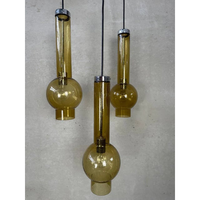 A set of 3 vintage hanging lamps from staff leuchten. Model: p1115. Amber colored blown glass tubes. Glass height: 47cm....