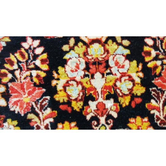 The blue field woven with flowering fan palmettes extending to a central floral spray and flower-filled urns within rust...