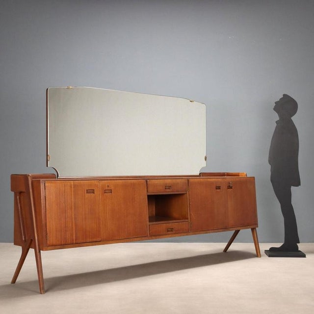 Vintage Italian-made cabinet with mahogany veneer, hinged doors, open compartment and drawers. This piece is attributed to...