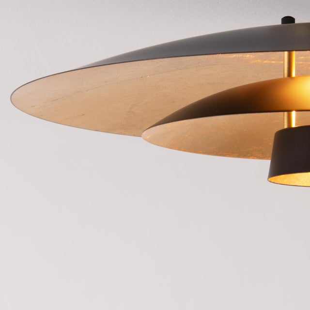 The Rancho Mirage Float Arc Lamp is a dimmable arc lamp with a Weathered Brass steel body and a FLEUR Matte Black/Gold...