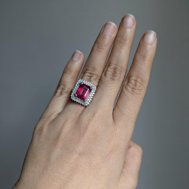 A Madagascar ruby glows in a vivid red at the heart of this solid 14K white gold ring, flanked by fifty-two earth-mined...