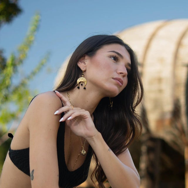 Bring an aura of mystery and elegance to your style with the Mystic Moon Onyx Dangle Gold Earrings. Crafted from bronze...