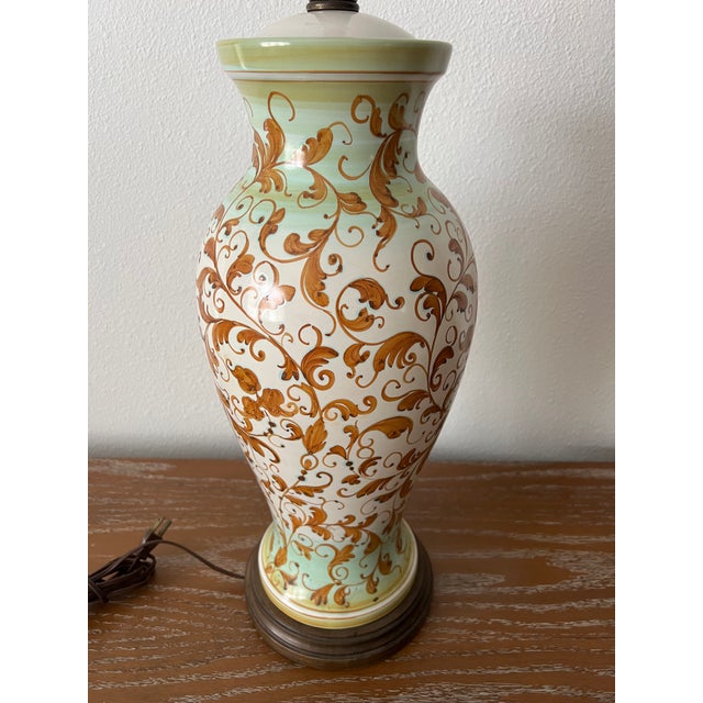 A beautifully hand-painted vintage ceramic table lamp featuring an elegant all-over scrolling foliate motif in warm ochre...