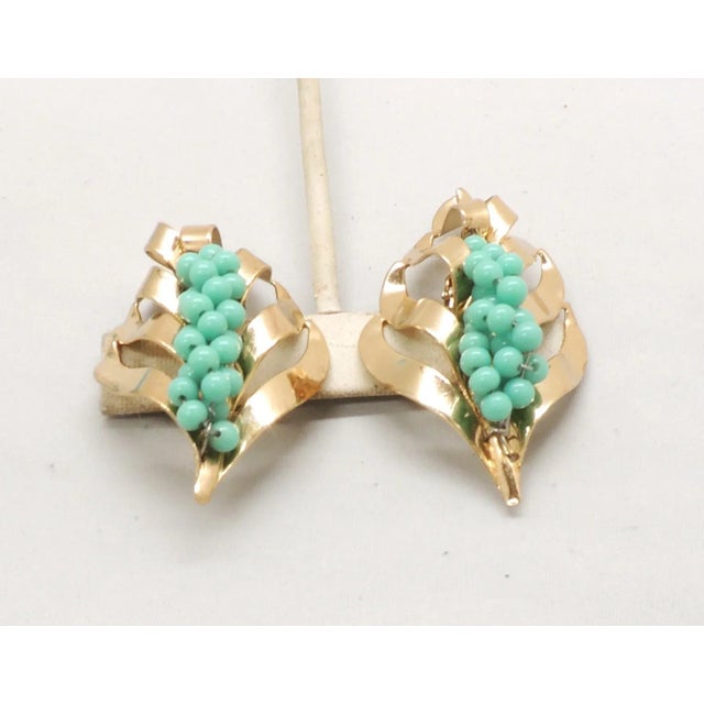 This is part of Chairish’s Costume Jewelry assortment. 1950s goldtone faux-turquoise beaded leaf clip earrings. Marked...