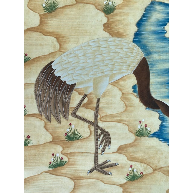 This painting serene natural scene where two graceful cranes stand beside a gently flowing stream. One crane bends...