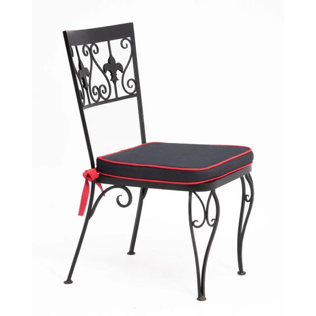 A stylish set of six wrought iron dining chairs with mesh seats, hand tied seat cushions and Fleur-De-Lis decoration....