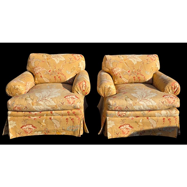 A comfortable and classically proportioned pair of English roll arm club chairs, upholstered in a warm golden ground...