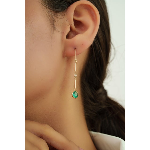 These elegant drop earrings feature 2.15 carats of round emerald set in 14K yellow gold. Each emerald measuring 7 mm in...