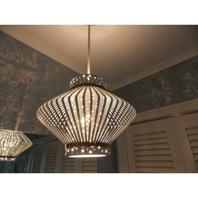 A stunning mid century modernist space age hanging light attributed to Ernest IgL. It features a metal cylindrical white...