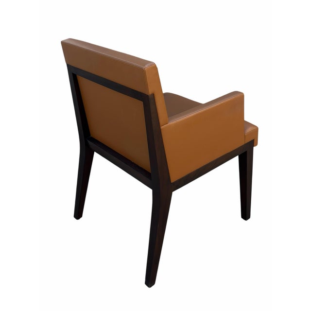 Pair of Holly Hunt Walnut and Leather Dining Chairs. This pair of armchairs is upholstered in cognac leather, and signed...