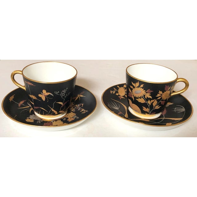 These beautifully hand painted cups and saucers have raised decoration in floral, bird and insect designs on a matte black...