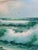 A large, atmospheric seascape oil painting capturing crashing turquoise waves beneath a soft blue sky dotted with...