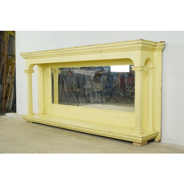 Vintage fireplace mantel with an integrated overmantel mirror. It features Corinthian style columns on either side and a...