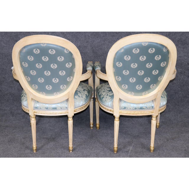 This elegant suite of Louis XVI-style dining chairs presents a refined combination of painted wood, restrained parcel-gilt...