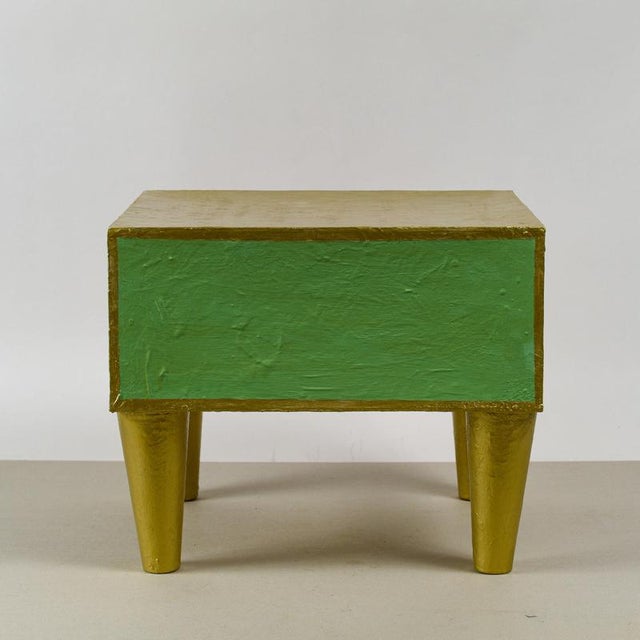 This unique side table, crafted from cardboard and entirely hand-painted, presents itself as an artistic design object...