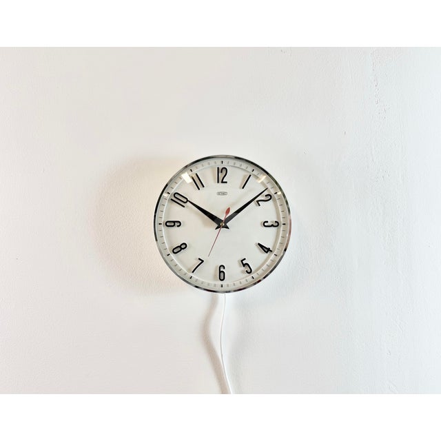 Metamec wall clock was made in United Kingdom during the 1970s. It features a white bakelite body with a chrome ring, an...
