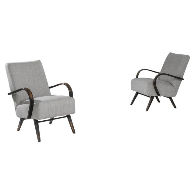 Indulge in mid-century modern design with this exquisite pair of 1950s Czech wooden armchairs by J. Halabala. The chairs...