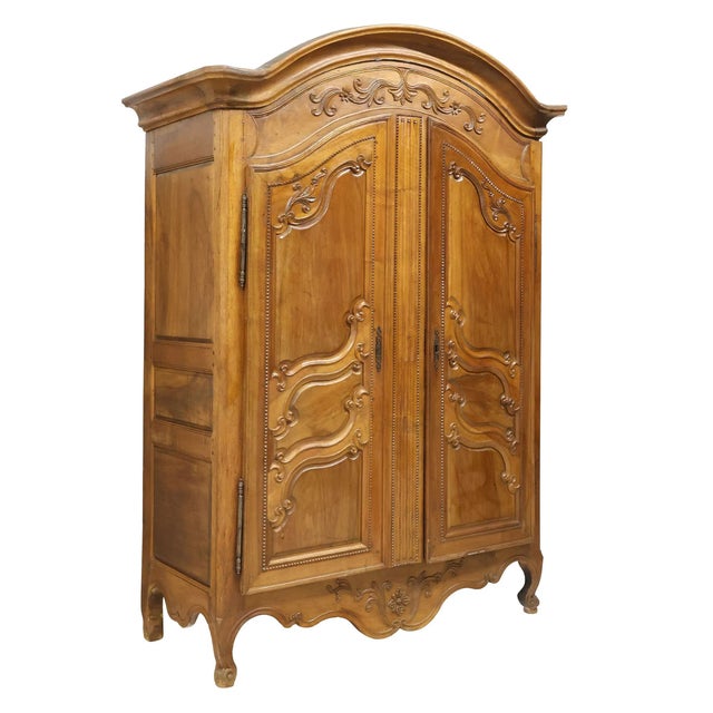 A handsome French Provincial carved walnut armoire dating to the 18th century, displaying the graceful curves and...