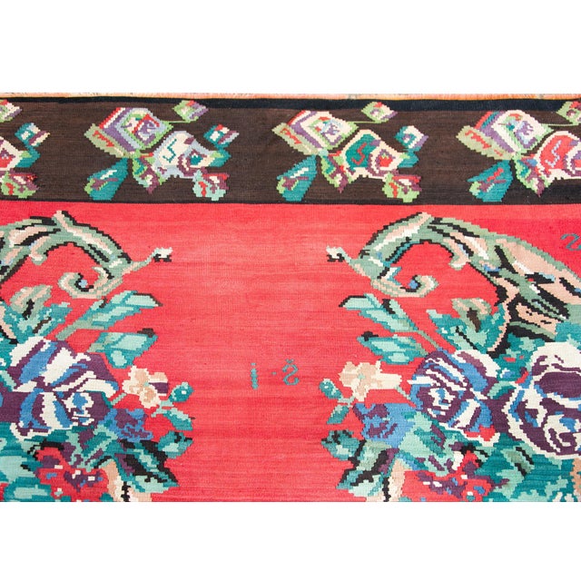 A cold vintage Turkish kilim rug with five large rose bouquet clusters in the center, set against a crimson background,...