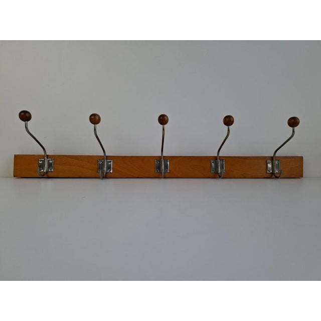 A classic midcentury wall coat rack crafted from wood and metal, produced in Czechoslovakia circa 1960. The design...