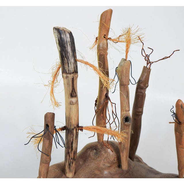 Contemporary driftwood assemblage figural sculpture. Larger wood base with eight carved stick figures with faces, fiber...