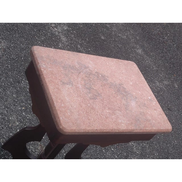 An antique parlor table offers beveled marble top over walnut base having four shaped supports with central turned column,...