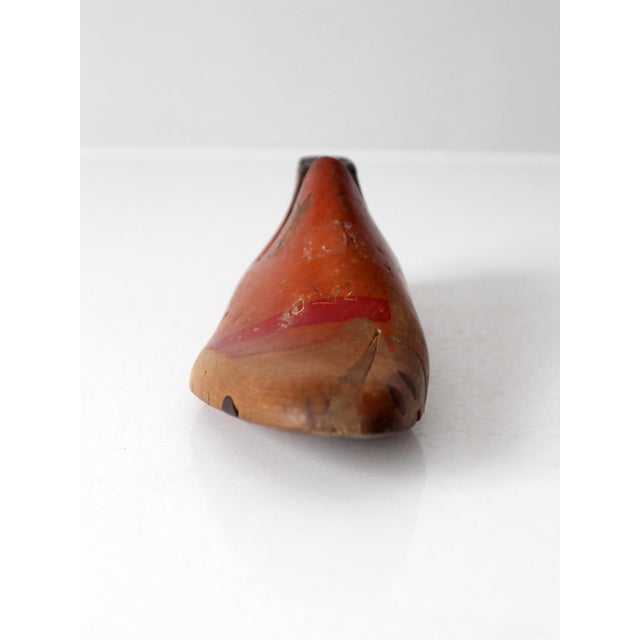 Antique early 20th-century wooden shoe last with red-painted detailing, handwritten markings, and a metal heel plate. Its...