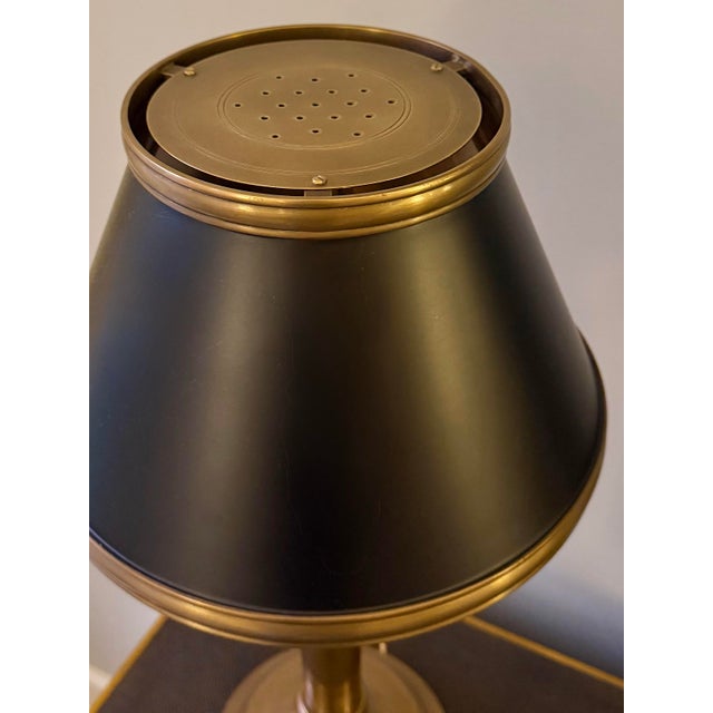 A Chapman & Myers library lamp for Visual Comfort with a warm brass finish, slender column, and black metal shade edged in...