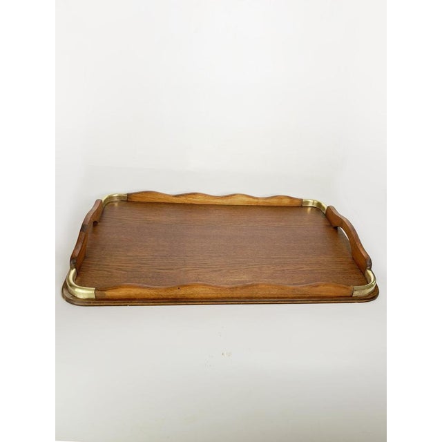An elegant rectangular solid wood tray, featuring a surrounding wooden gallery with brass fittings accentuating the...