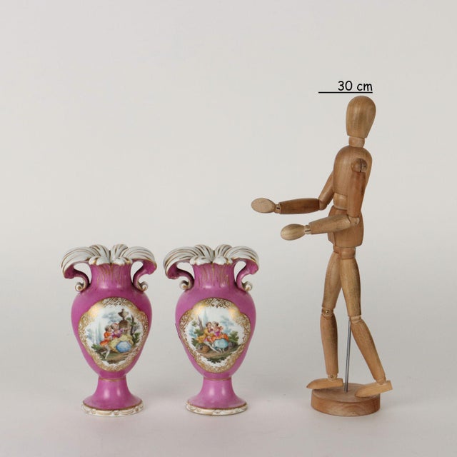 Pair of pink ground porcelain vases with gold decorations. In reserves painted with pairs of lovers. Under base maker's...