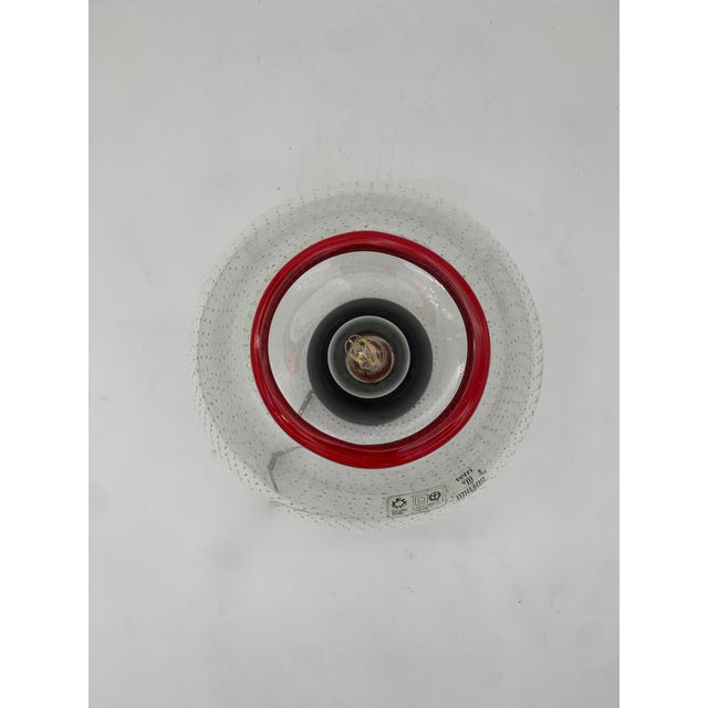 This wall or ceiling light by Leucos features a clear blown glass diffuser with a flattened, rounded shape. It features a...