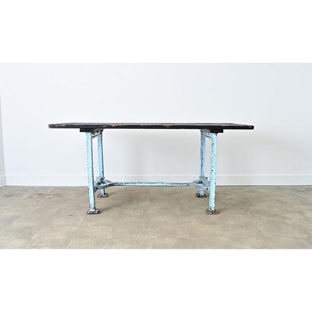 An antique French industrial work table/kitchen island from the early 20th century, whose robust design is a practical...