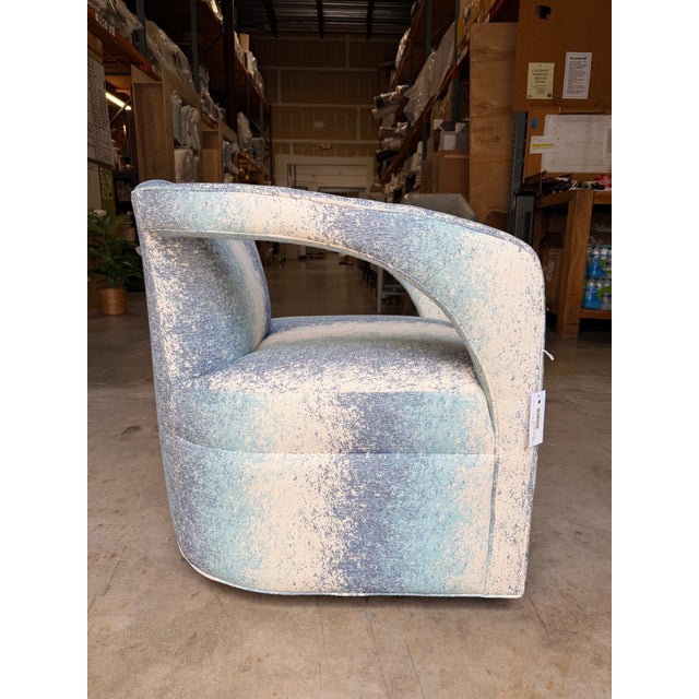 Contemporary swivel accent chair upholstered in a striking abstract fabric featuring layered shades of sky blue, soft...