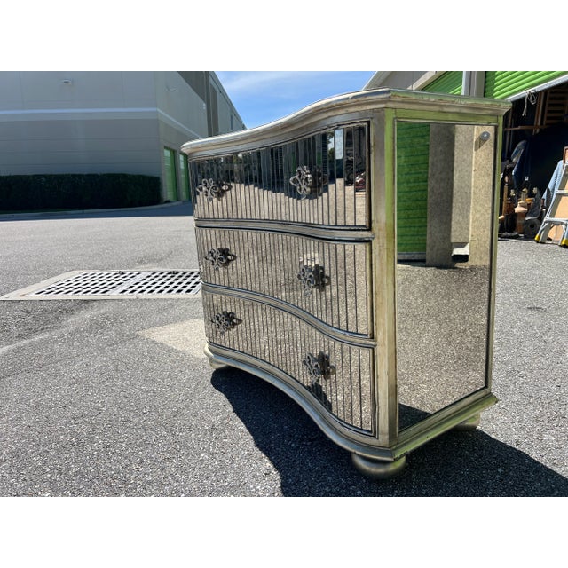 A stunning and large-scale serpentine front fully mirrored chest of drawers with silver plate drawer pulls