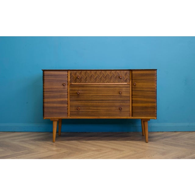 Compact mid century sideboard by Uniflex with striped walnut veneer, chevron drawer detail and tapered legs. Originally...