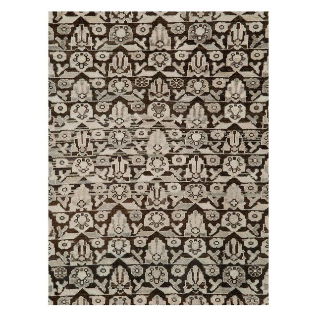 This early 20th-century Persian Malayer rug presents a tightly organized allover floral design across a deep brown field....