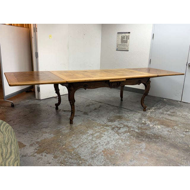 Design Plus Gallery presents a Mid 20th Century French Louis XV Extension Dining Table. The oak table displays intricate...