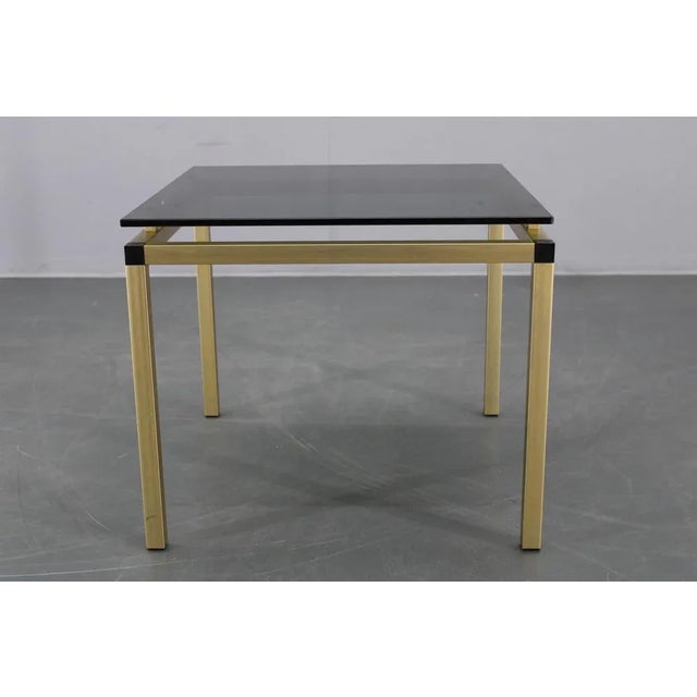 Italian coffee or side table made in the 1970s, featuring a robust aluminum skeletal frame finished in matte brass and a...