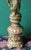 An elaborately carved tall candlestick holder featuring raised angel figures in a prayerful pose. The design showcases...