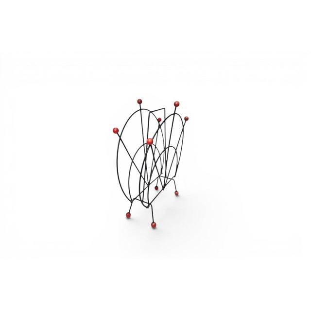 A delightful 1950s Danish atomic-age magazine rack in steel and teak — a small object with outsized personality. The...