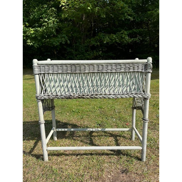A single antique rectangular woven wicker plant stand with four legs and a metal liner with green painted finish. Insert...