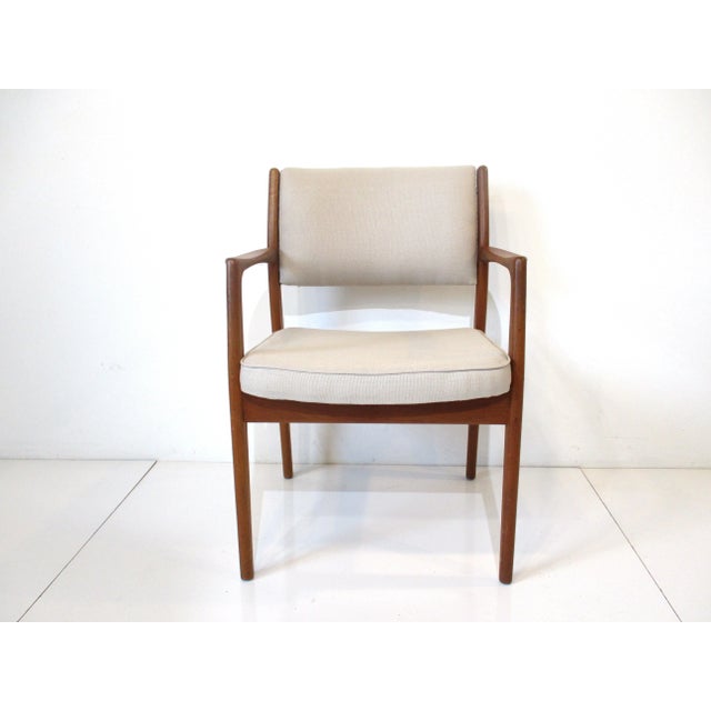 A very well crafted solid teak wood occasional chair with a mid toned cream linen upholstery having flared arms for...