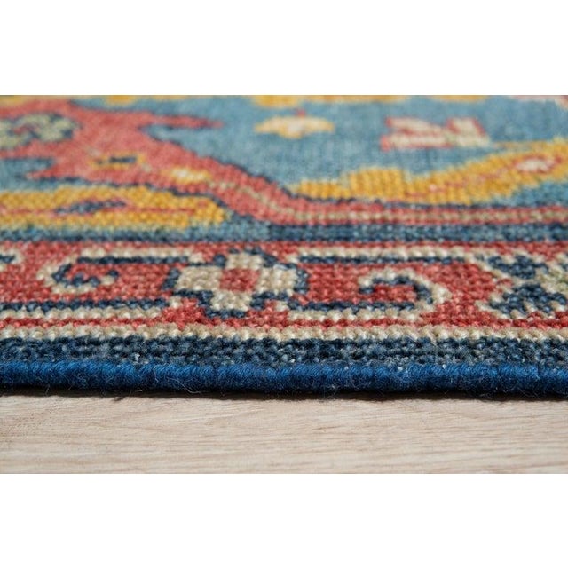 This blue wool rug features a hand knotted pile construction and originates from India. It is a substantial floor covering...
