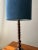The long, turned wooden base makes this table lamp strikingly slender. Various rounded volumes flow smoothly into one...