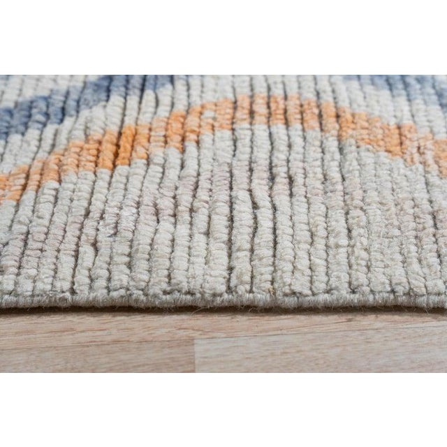 This gray wool rug is a hand knotted pile carpet featuring a classic Berber style. Crafted in Pakistan, it presents a...