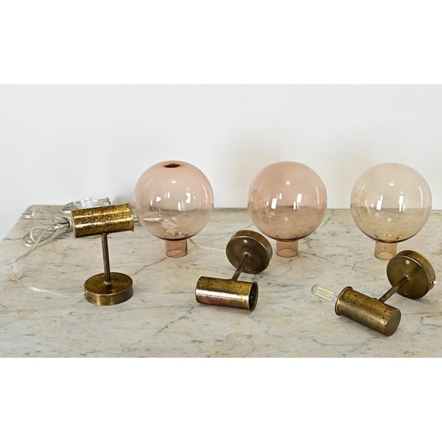 Dimensions: 9 ¼” H x 5 ¾” W x 7 ⅞” D Vintage set of three Swedish brass & smoked glass wall sconces designed by Hans-Agne...