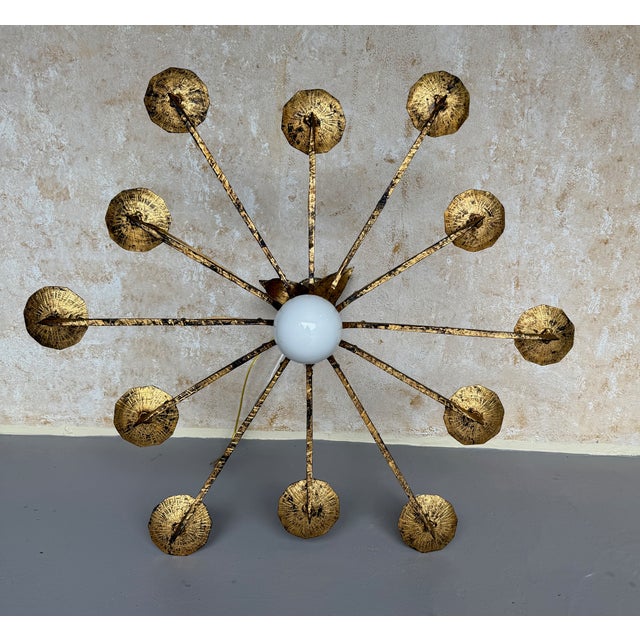 A striking Spanish gilt iron chandelier from the 1950s, featuring twelve radiating arms surrounding a central opaline...