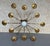 A striking Spanish gilt iron chandelier from the 1950s, featuring twelve radiating arms surrounding a central opaline...