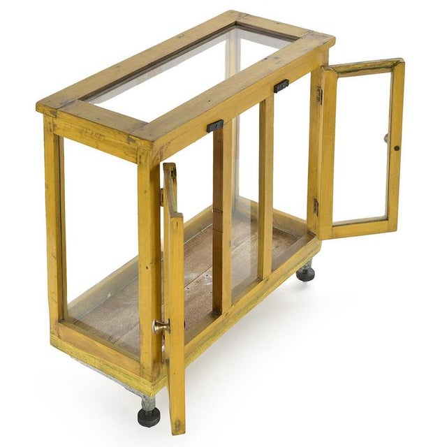 This small wooden display case, enhanced with a cheerful yellow patina, seduces with its design that is both functional...