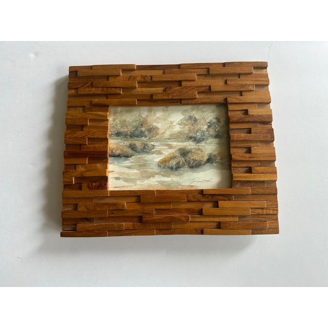 Monochromatic landscape featuring water, rocks and trees. Signed and framed.